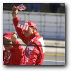 Rubens Barrichello to the left and Michael Schumacher to the right proudly wave the American flag.