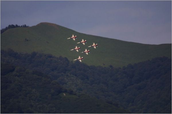 Taken with a zoom lens. They are flying over a mountain top.