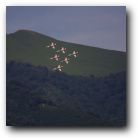 Taken with a zoom lens. They are flying over a mountain top.