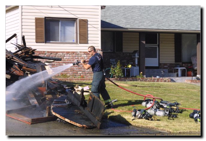 It was a hot and windy day so the fireman kept the burned and hot debris cool