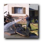 It was a hot and windy day so the fireman kept the burned and hot debris cool